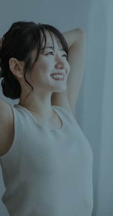 窓辺で日に当たる薄着の女性